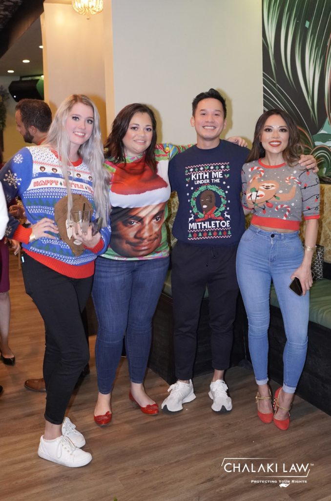 three women and a man in Christmas sweaters